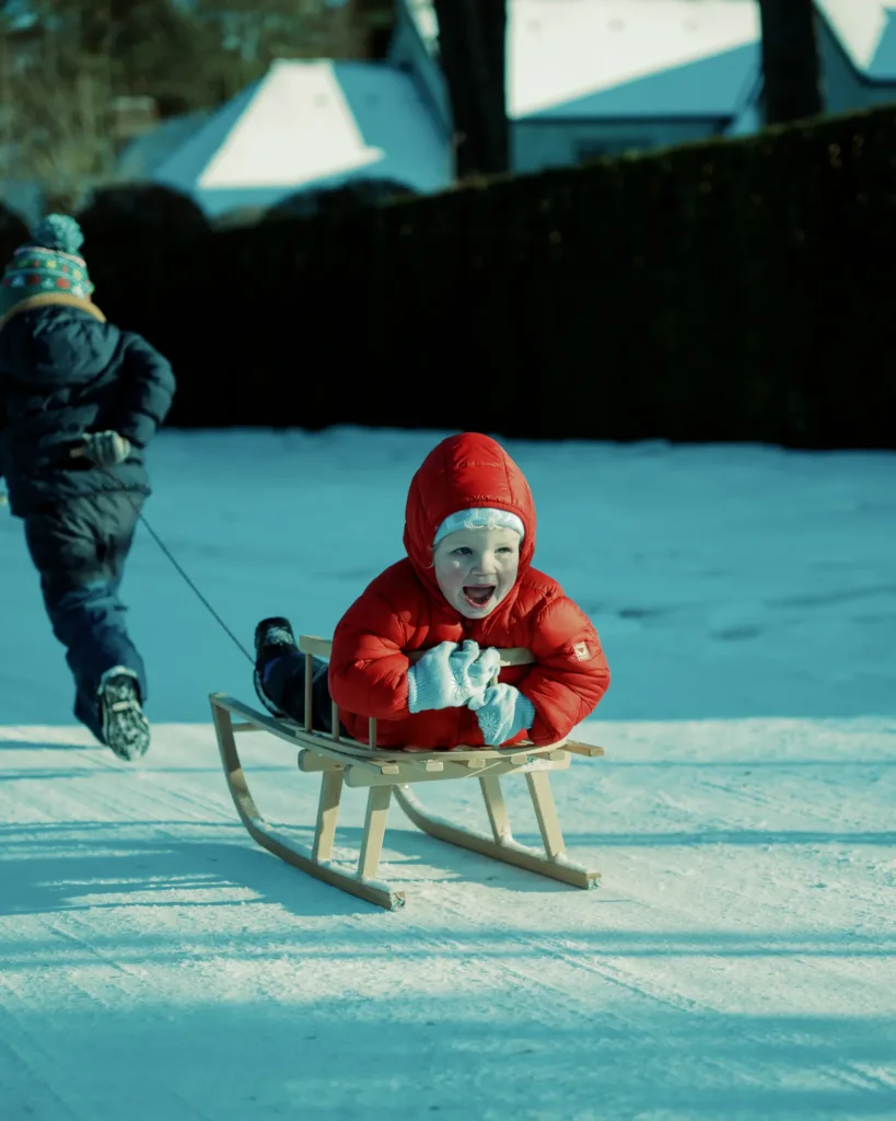 child sledding snowy park joyful